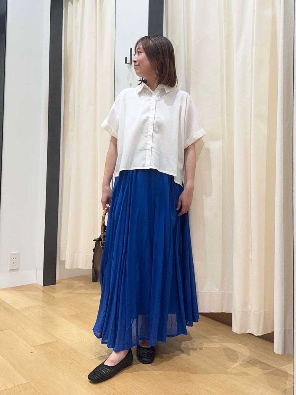 ブラック系のバレエシューズ、ブルー系のスカート、ホワイト系のシャツ/ブラウスを着用したレディースの夏コーディネートの5枚目の写真