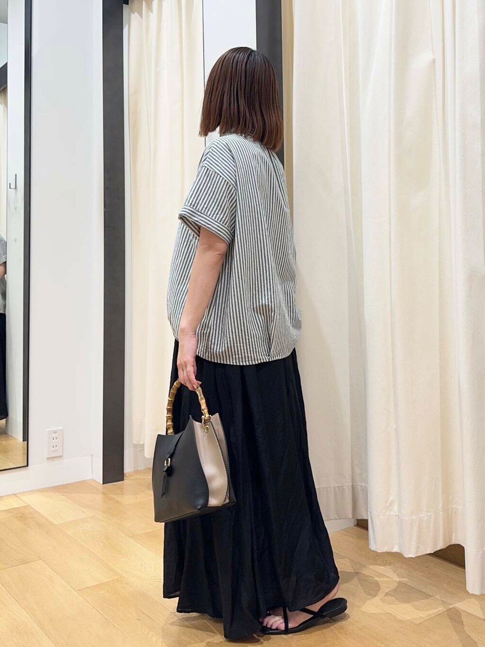 ブラック系のサンダル、ブラック系のハンドバッグ、ブラック系のスカートを着用したレディースの夏コーディネートの2枚目の写真