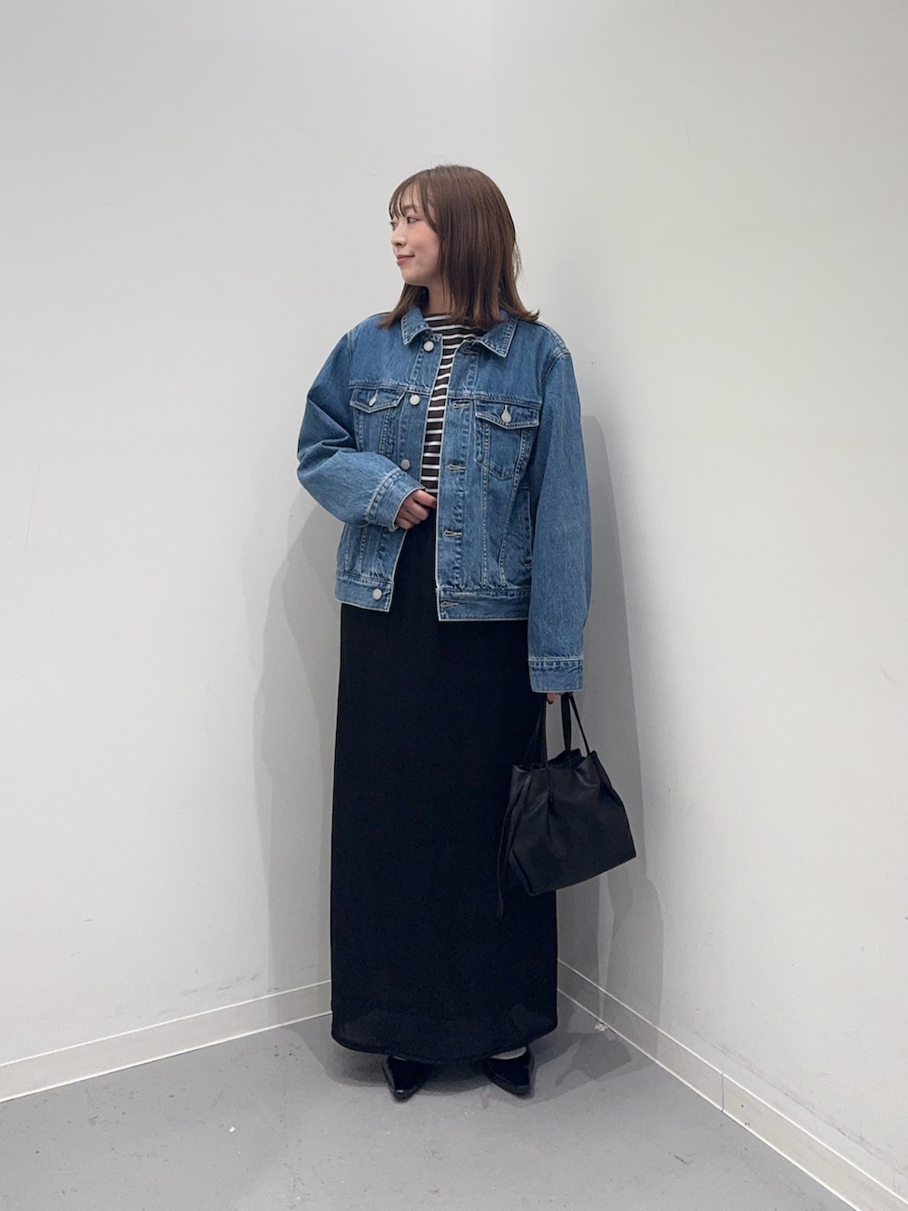 ブルー系のデニムジャケット、ブルー系のTシャツ/カットソー、ブラック系のスカートを着用したレディースの冬コーディネートの2枚目の写真