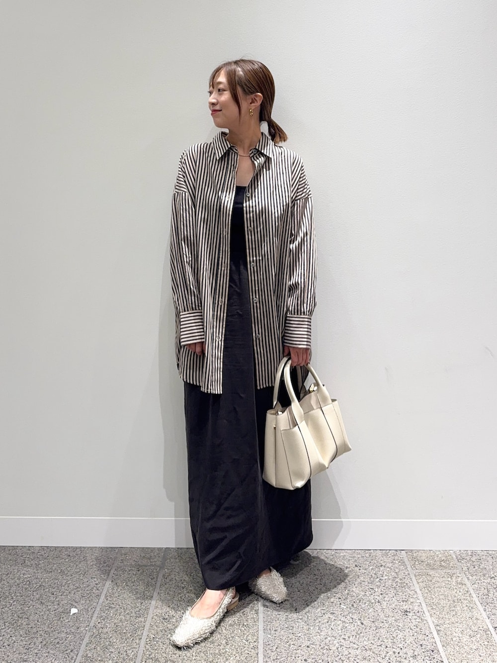 グレー系のシャツ/ブラウス、ブラウン系のスカート、ホワイト系のトートバッグを着用したレディースの秋コーディネートの2枚目の写真