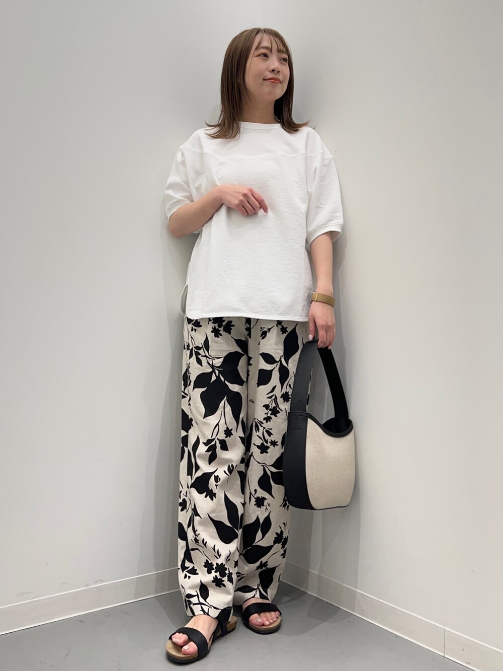 ホワイト系のTシャツ/カットソー、ベージュ系のその他パンツ、ブラック系のハンドバッグを着用したレディースの春コーディネートの2枚目の写真