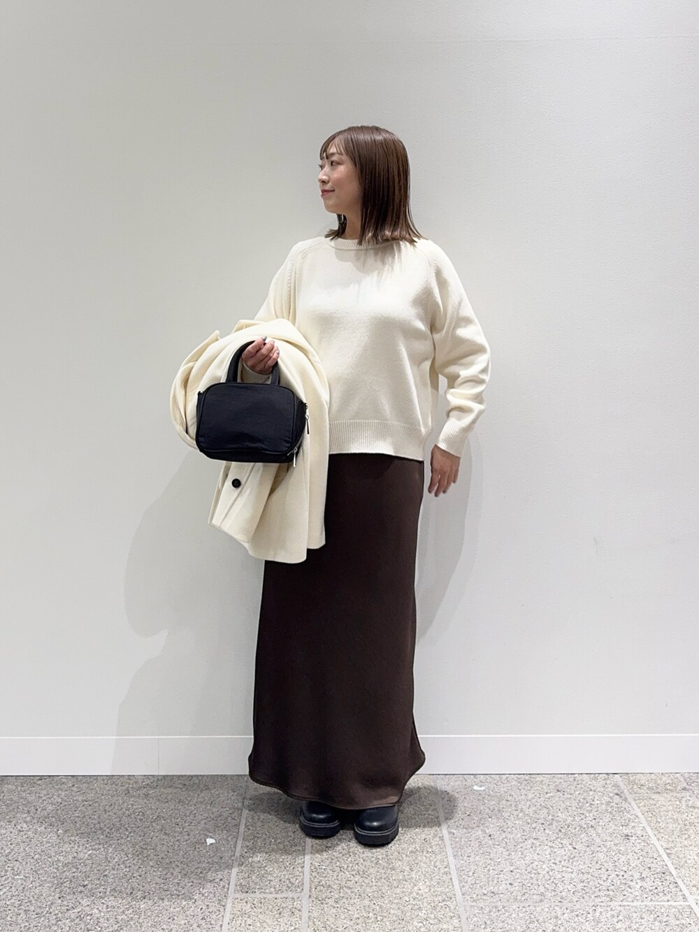 ホワイト系のピーコート、ホワイト系のニット/セーター、ブラック系のボストンバッグを着用したレディースの冬コーディネートの5枚目の写真