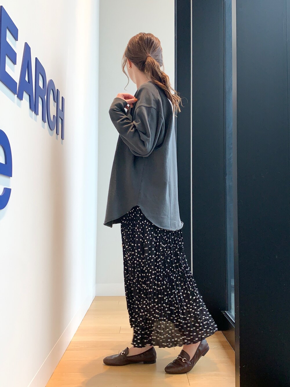 ブラック系のTシャツ/カットソー、ブラック系のスカート、ブラウン系のローファーを着用したレディースの冬コーディネートの2枚目の写真