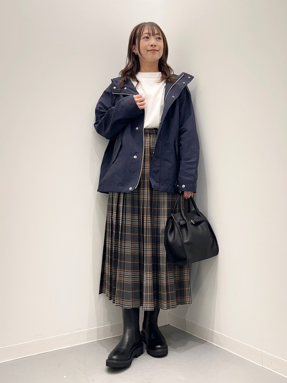 ホワイト系のTシャツ/カットソー、グレー系のスカート、ブルー系のダウンベストを着用したレディースの秋コーディネートの8枚目の写真