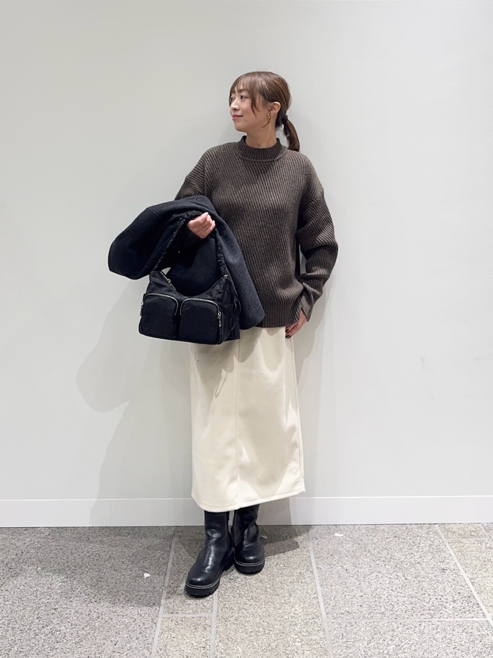 グレー系のピーコート、ブラウン系のニット/セーター、ホワイト系のスカートを着用したレディースの冬コーディネートの6枚目の写真