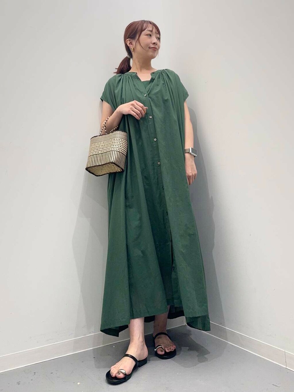 グリーン系のワンピース、ブラック系のサンダルを着用したレディースの夏コーディネートの2枚目の写真
