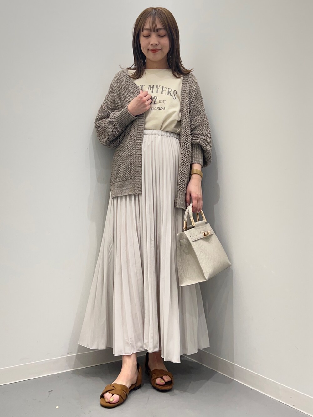 ベージュ系のTシャツ/カットソー、ホワイト系のスカート、グリーン系のカーディガン/ボレロを着用したレディースの春コーディネートの4枚目の写真