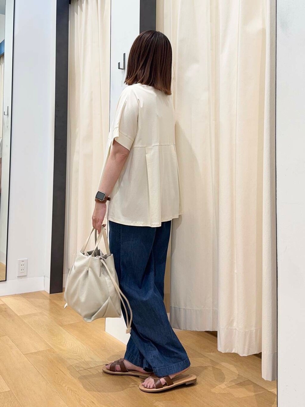 ブラウン系のサンダル、ブルー系のデニムパンツ、ホワイト系のショルダーバッグを着用したレディースの夏コーディネートの3枚目の写真