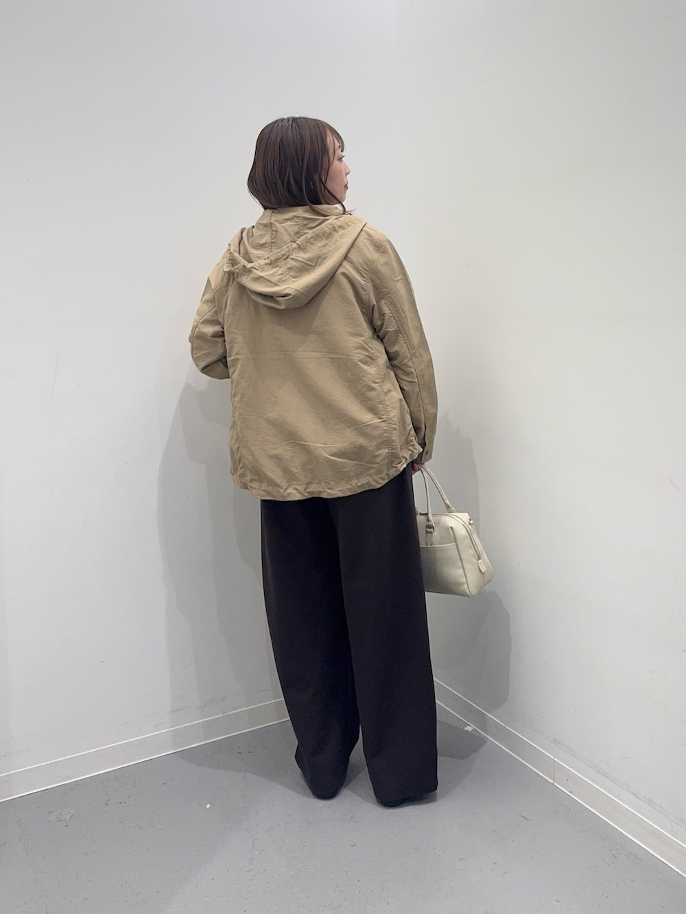 ホワイト系のニット/セーター、ベージュ系のナイロンジャケット、ブラウン系のその他パンツを着用したレディースの春コーディネートの2枚目の写真