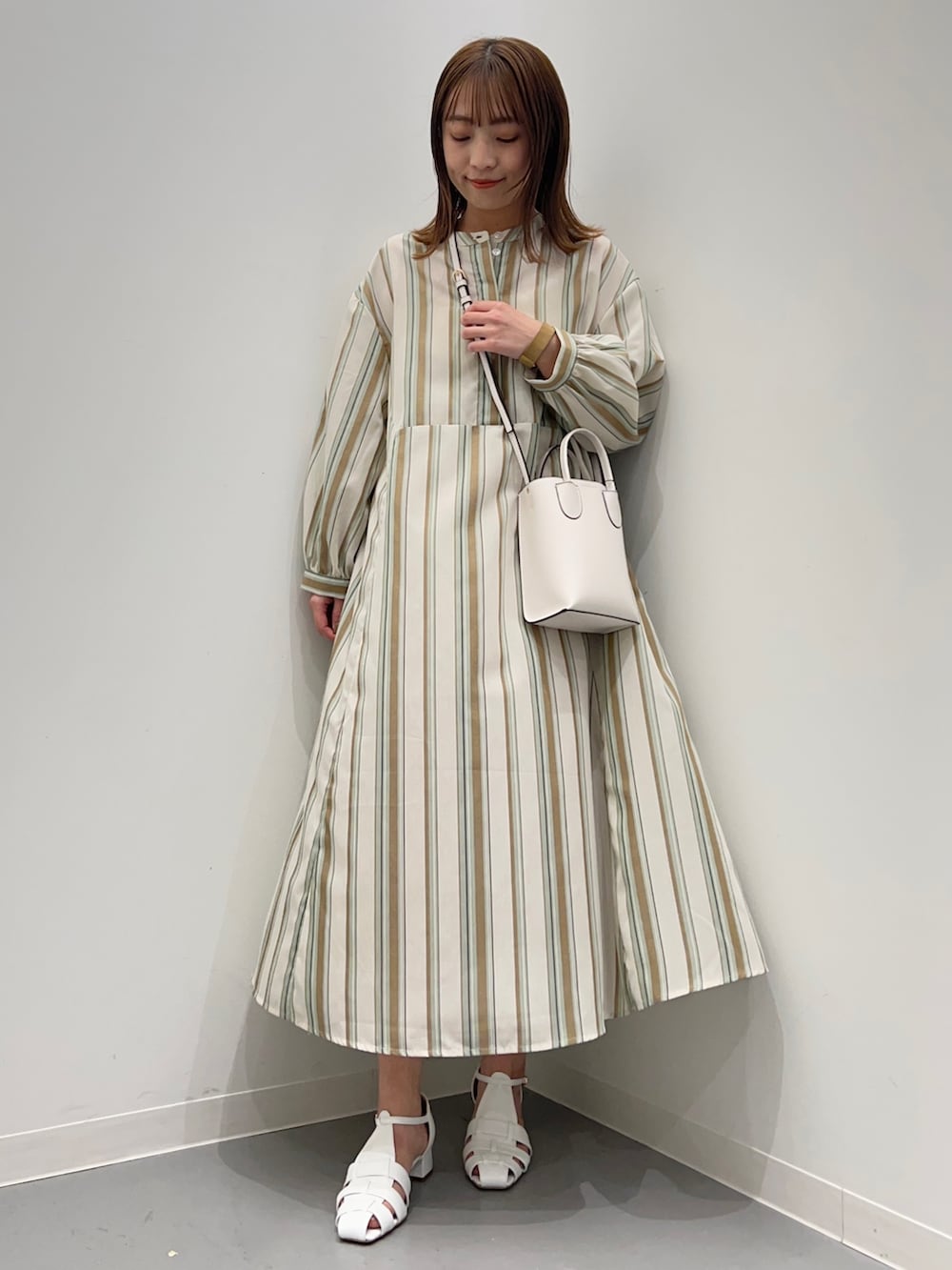 グリーン系のワンピース、ホワイト系のサンダルを着用したレディースの春コーディネートの3枚目の写真