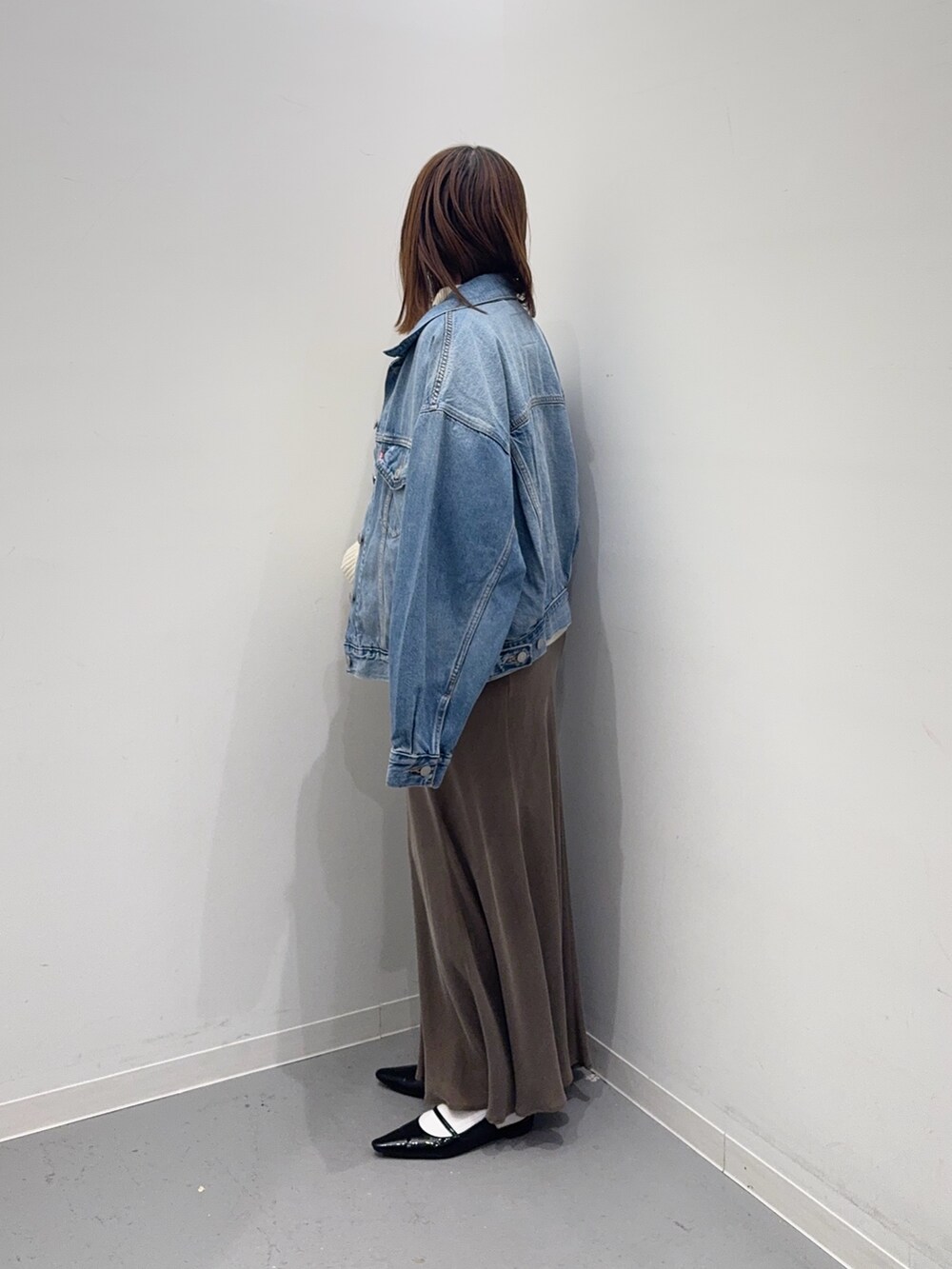 ホワイト系のニット/セーター、ブラウン系のスカート、ブルー系のデニムジャケットを着用したレディースの冬コーディネートの2枚目の写真