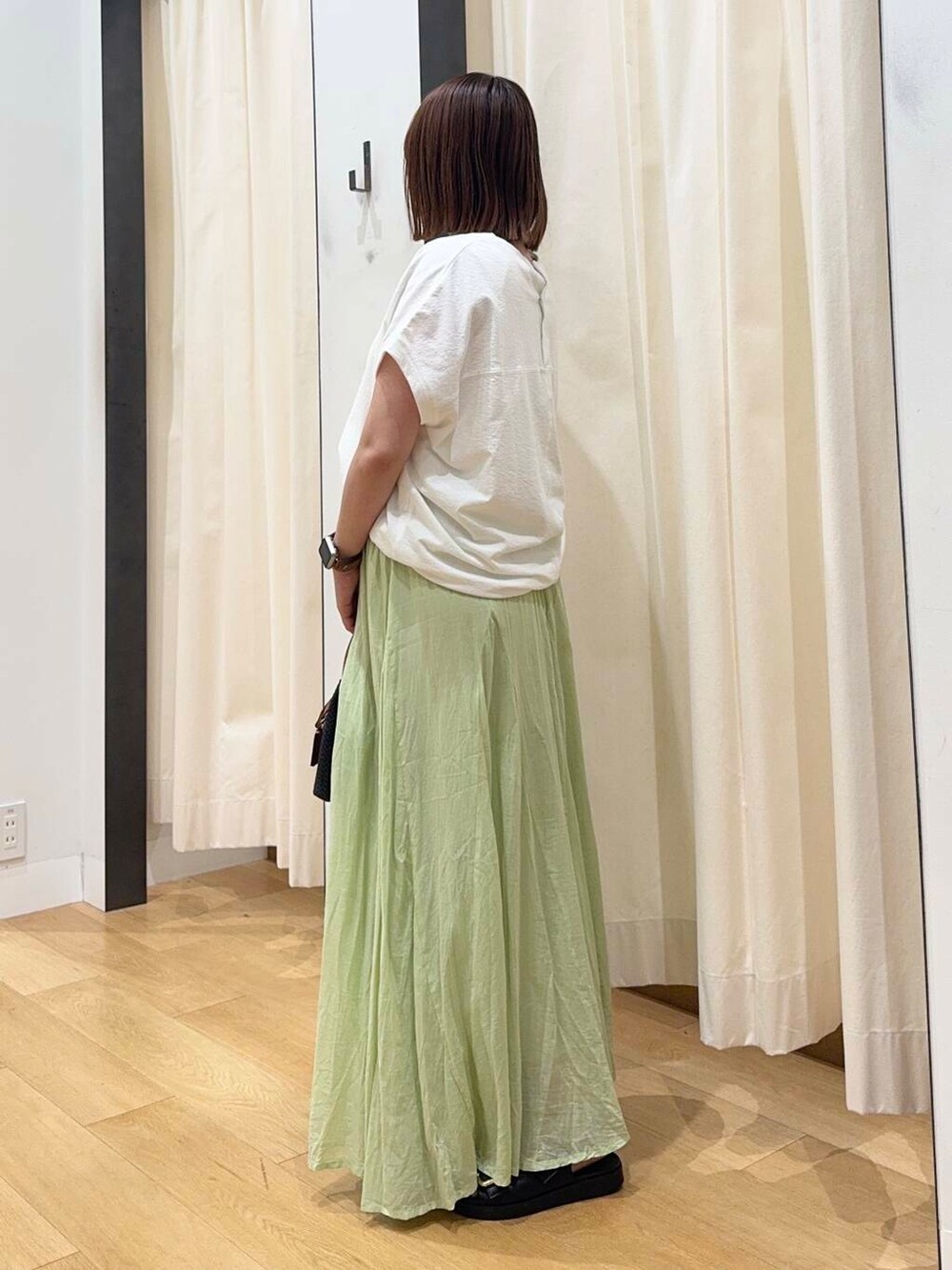 ブラック系のトートバッグ、ブラック系のサンダル、グリーン系のスカートを着用したレディースの夏コーディネートの3枚目の写真