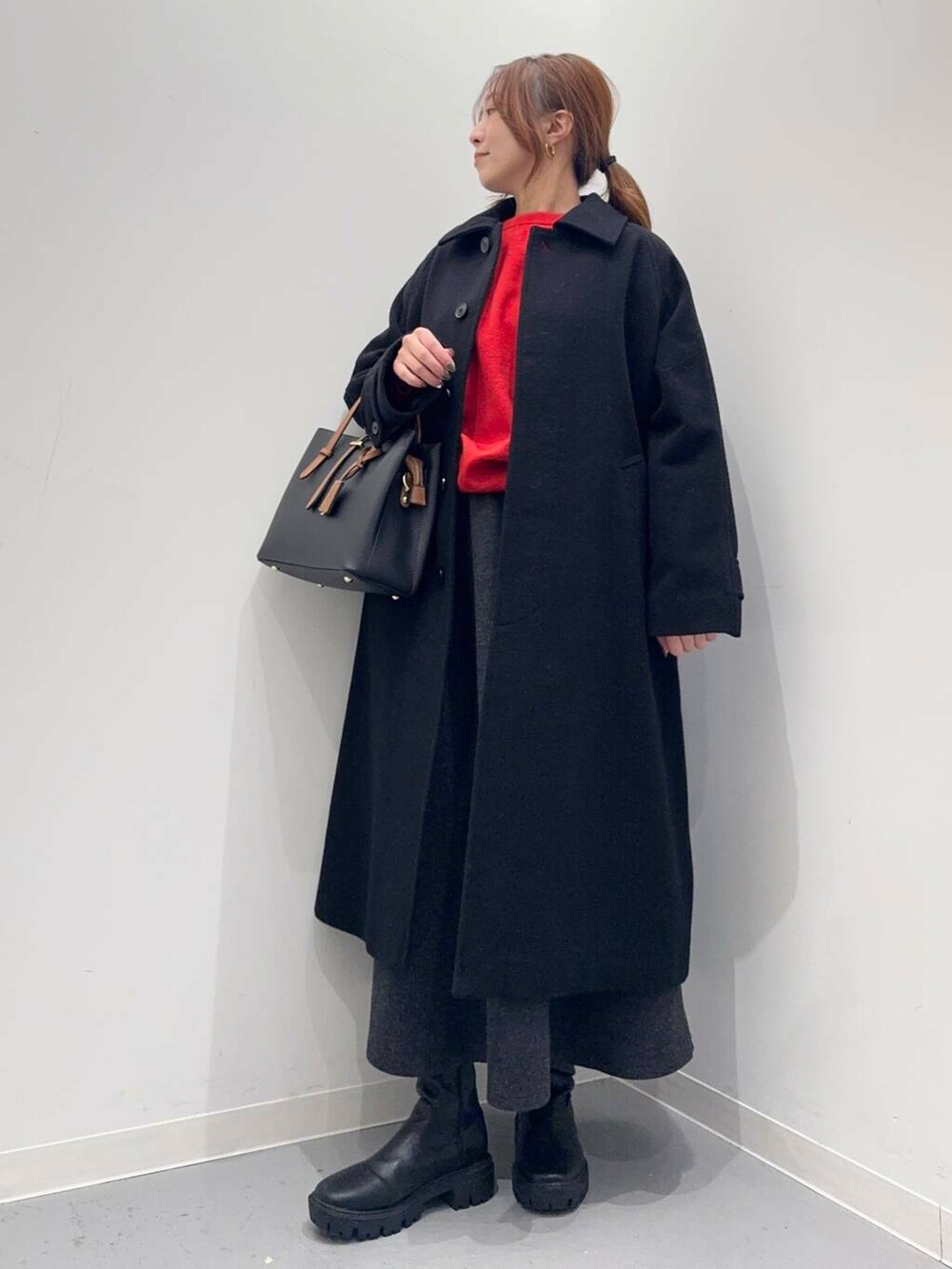ブラック系のトートバッグ、ブラック系のブーツ、レッド系のニット/セーターを着用したレディースの冬コーディネートの4枚目の写真