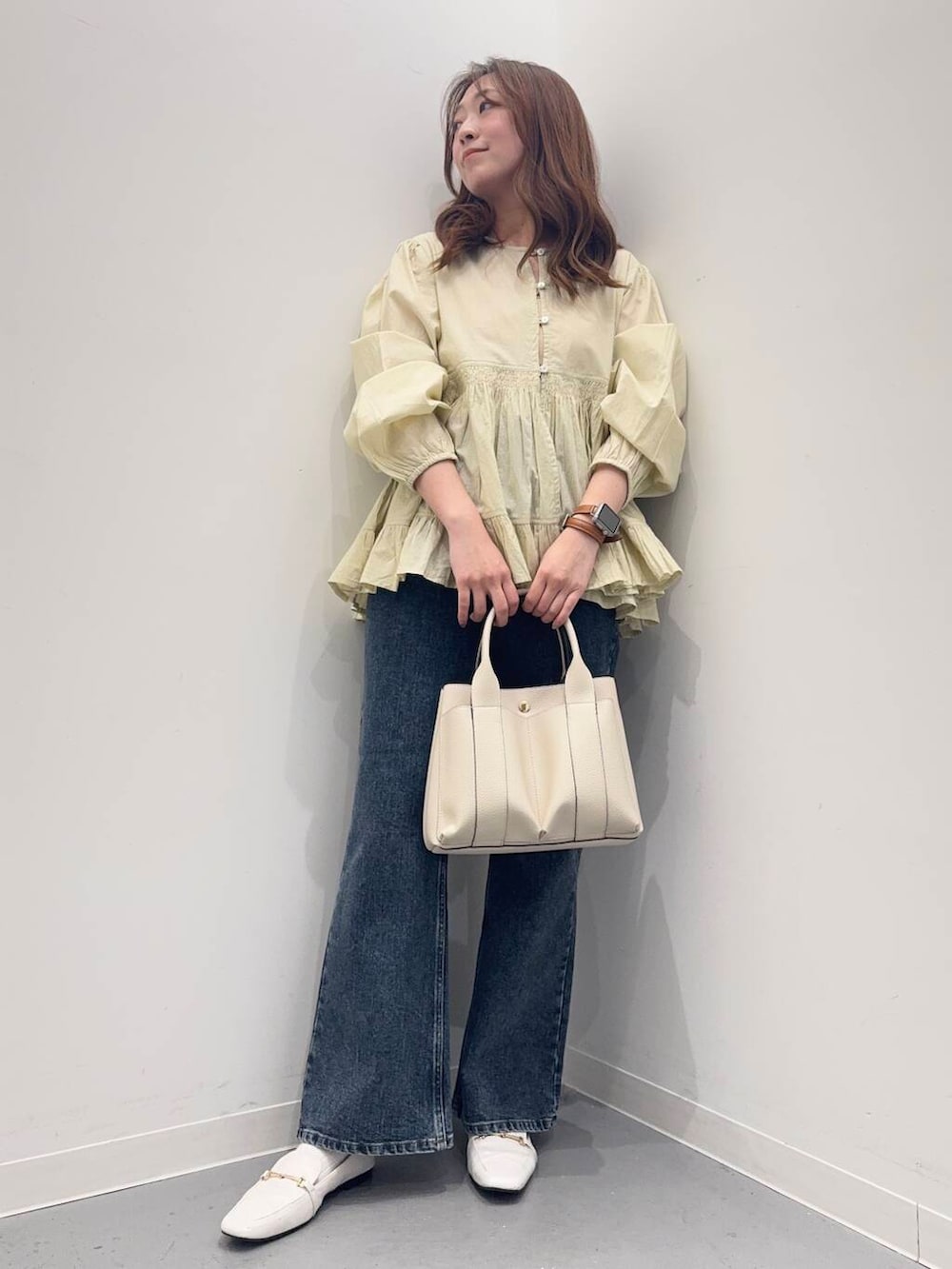 ホワイト系のトートバッグ、ブルー系のデニムパンツ、ホワイト系のローファーを着用したレディースの春コーディネートの6枚目の写真