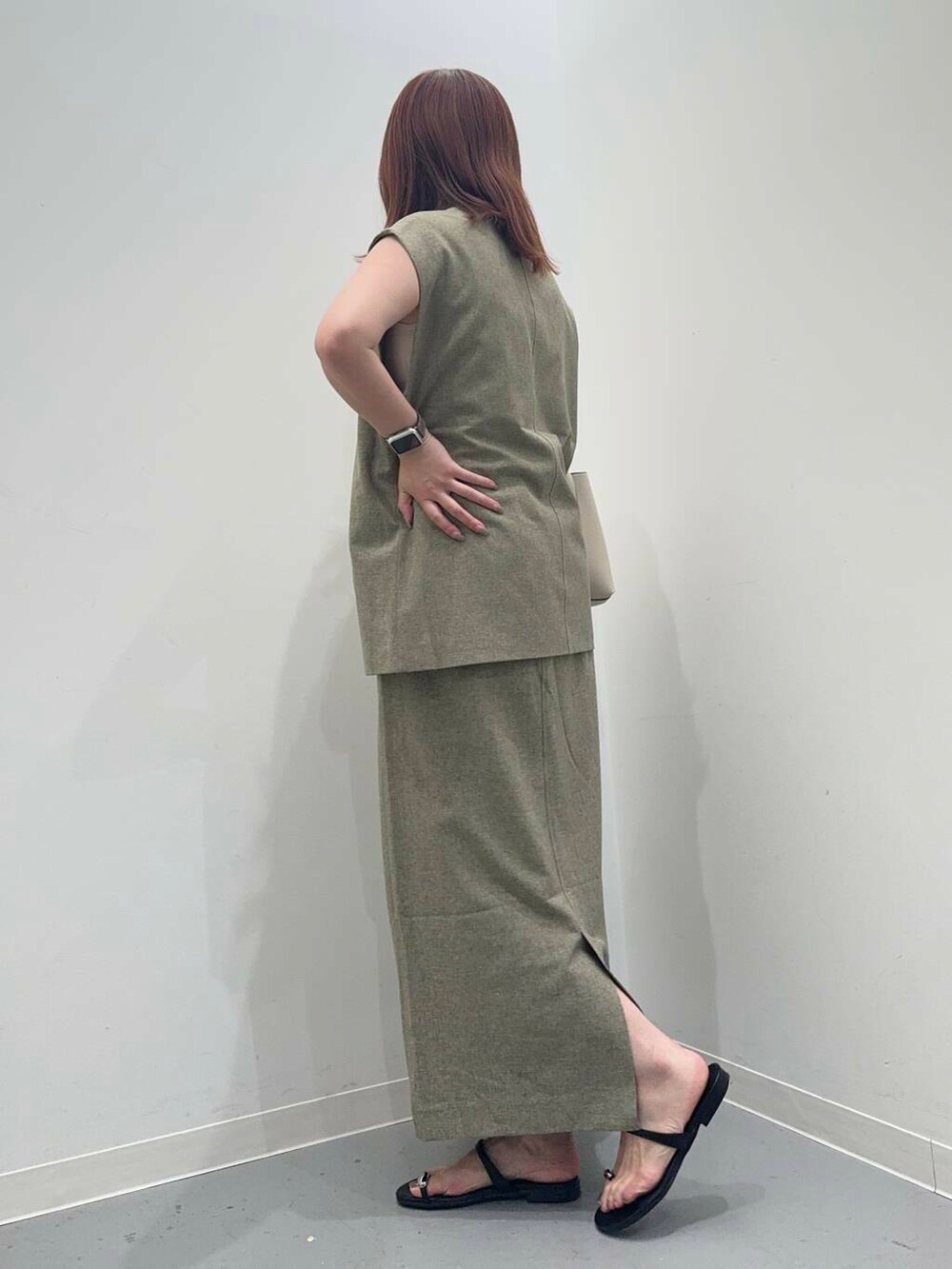 ホワイト系のトートバッグ、ブラック系のサンダル、グリーン系のベストを着用したレディースの夏コーディネートの2枚目の写真