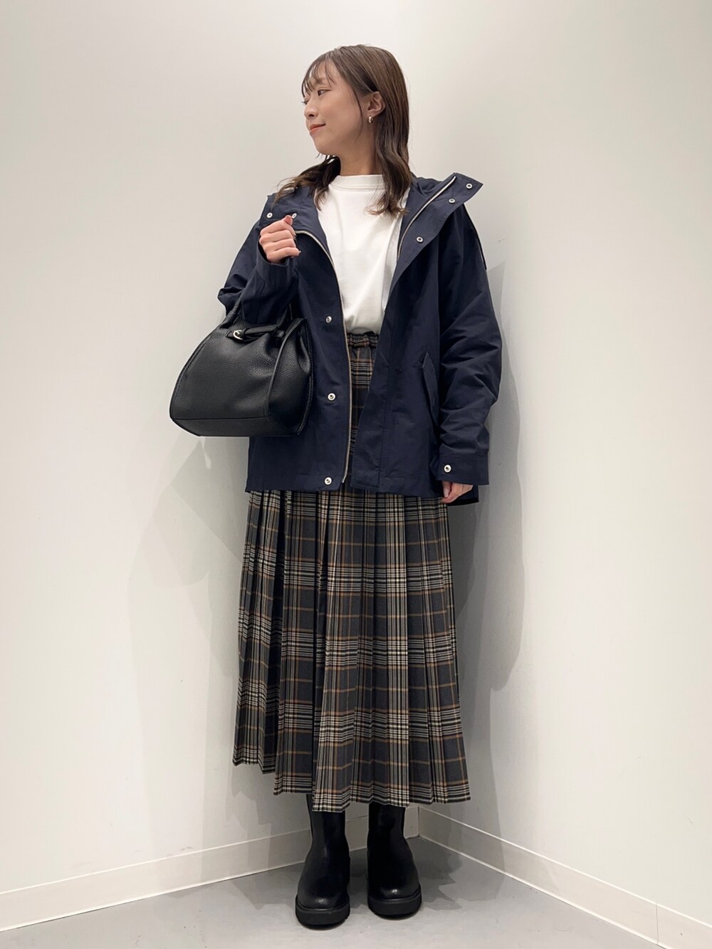 ホワイト系のTシャツ/カットソー、グレー系のスカート、ブルー系のダウンベストを着用したレディースの秋コーディネートの5枚目の写真