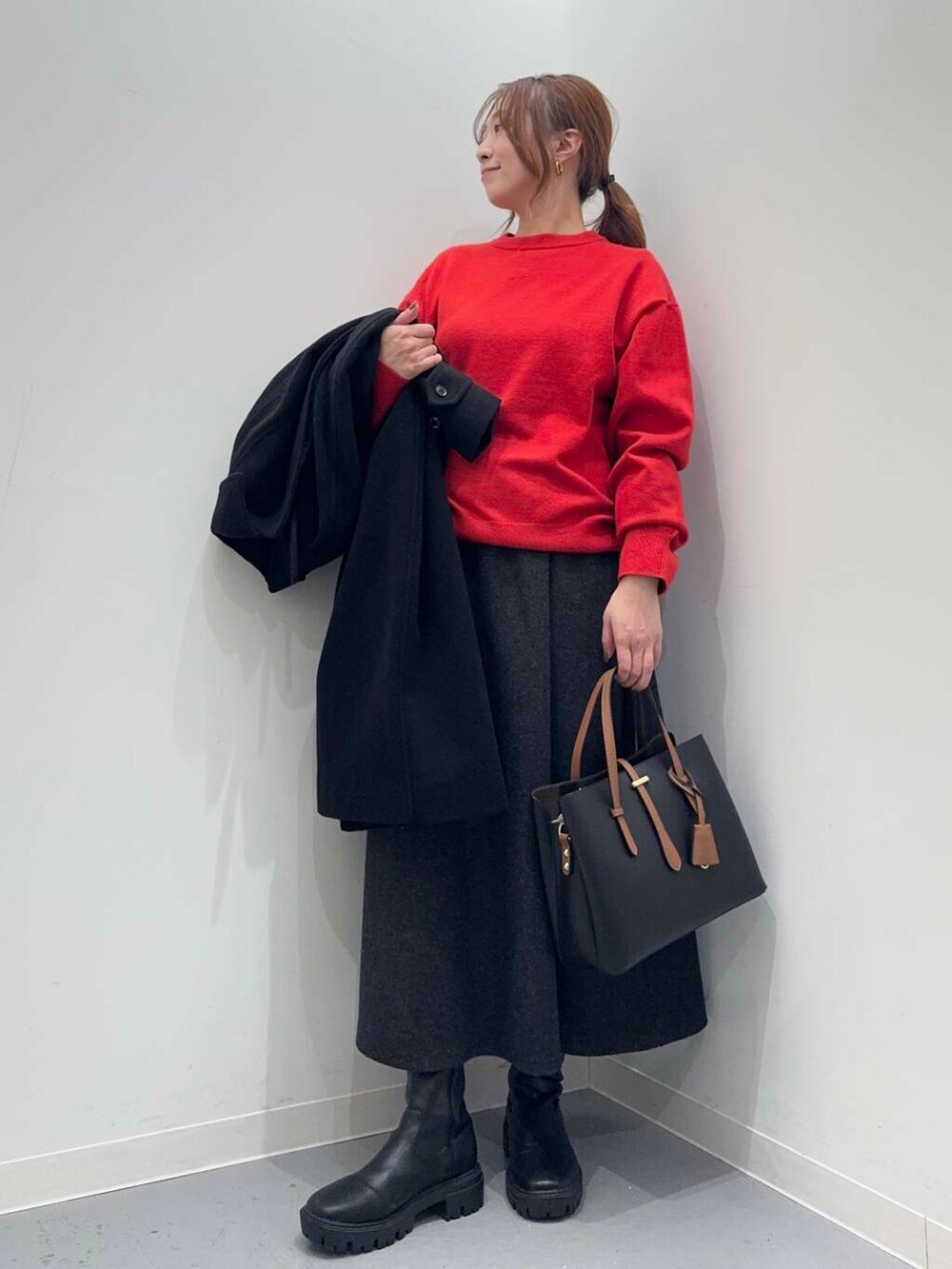 ブラック系のトートバッグ、ブラック系のブーツ、レッド系のニット/セーターを着用したレディースの冬コーディネートの8枚目の写真