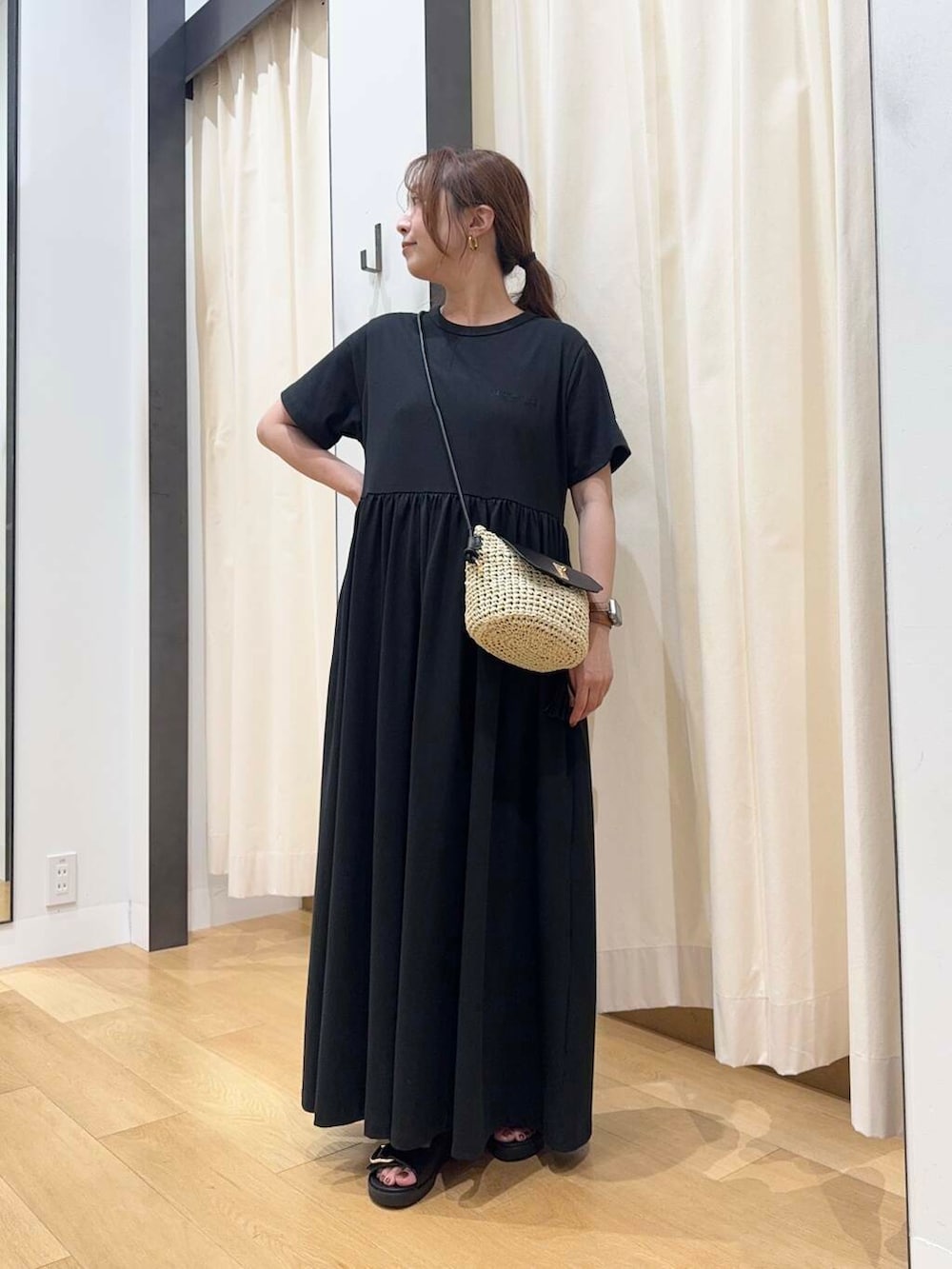 ベージュ系のショルダーバッグ、ブラック系のワンピース、ブラック系のサンダルを着用したレディースの春コーディネートの2枚目の写真