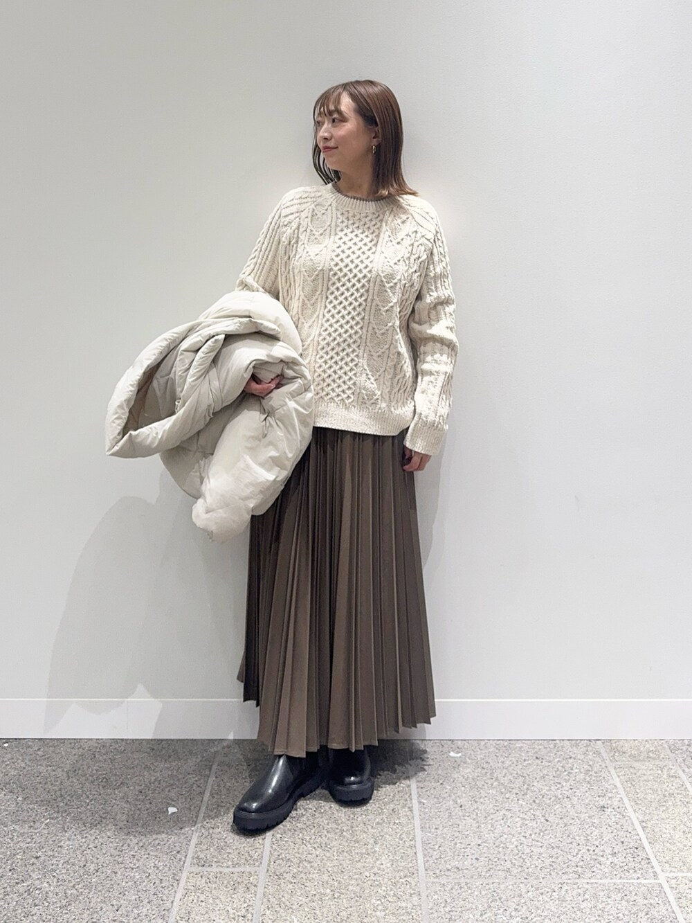 ホワイト系のダウンジャケット/コート、ホワイト系のニット/セーター、ベージュ系のスカートを着用したレディースの冬コーディネートの7枚目の写真
