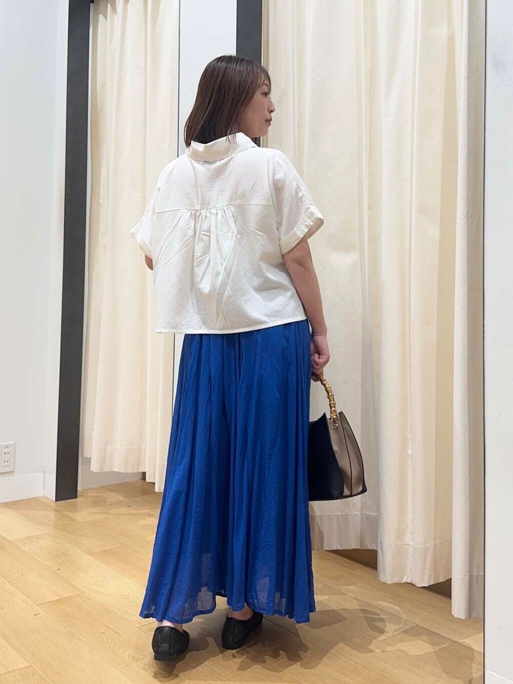 ブラック系のバレエシューズ、ブルー系のスカート、ホワイト系のシャツ/ブラウスを着用したレディースの夏コーディネートの4枚目の写真