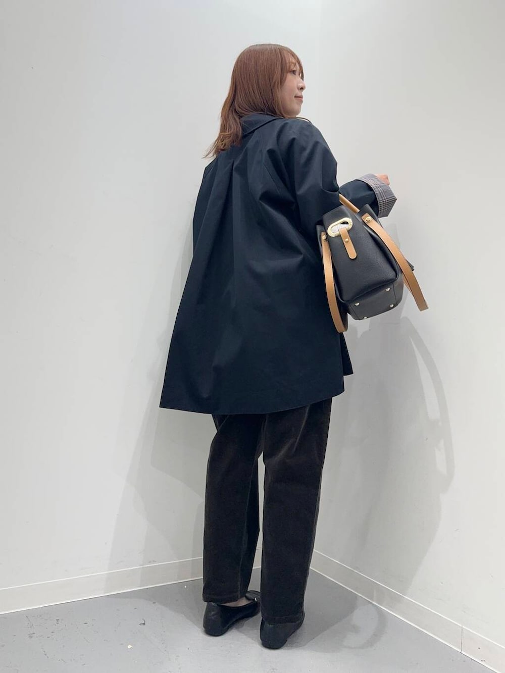 ブラック系のローファー、ブラック系のトートバッグ、ブルー系のステンカラーコートを着用したレディースの秋コーディネートの3枚目の写真