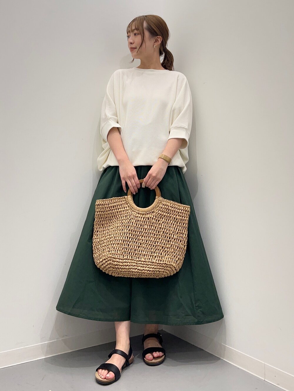 ベージュ系のTシャツ/カットソー、グリーン系のスカート、ブラック系のサンダルを着用したレディースの春コーディネートの3枚目の写真