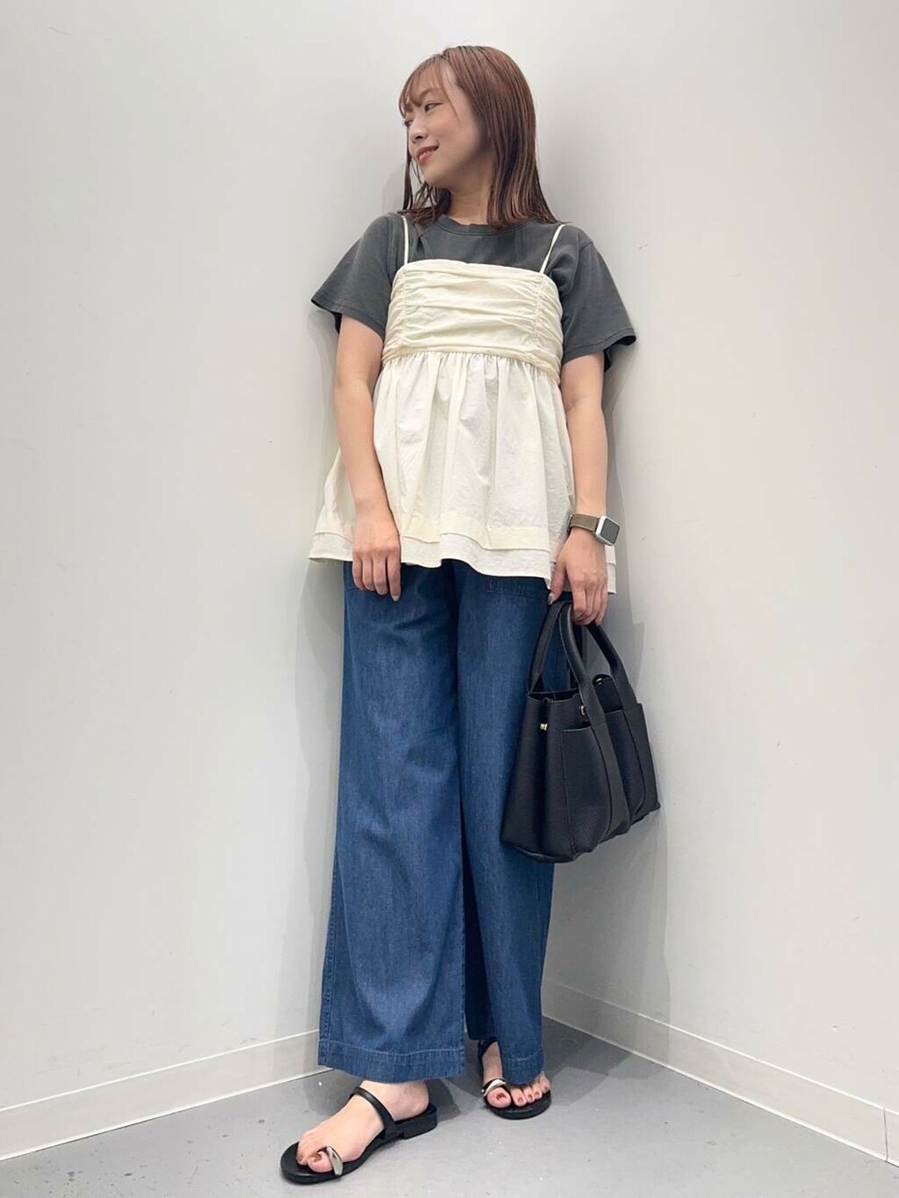 ブラック系のトートバッグ、ブルー系のデニムパンツ、ブラック系のサンダルを着用したレディースの夏コーディネートの5枚目の写真