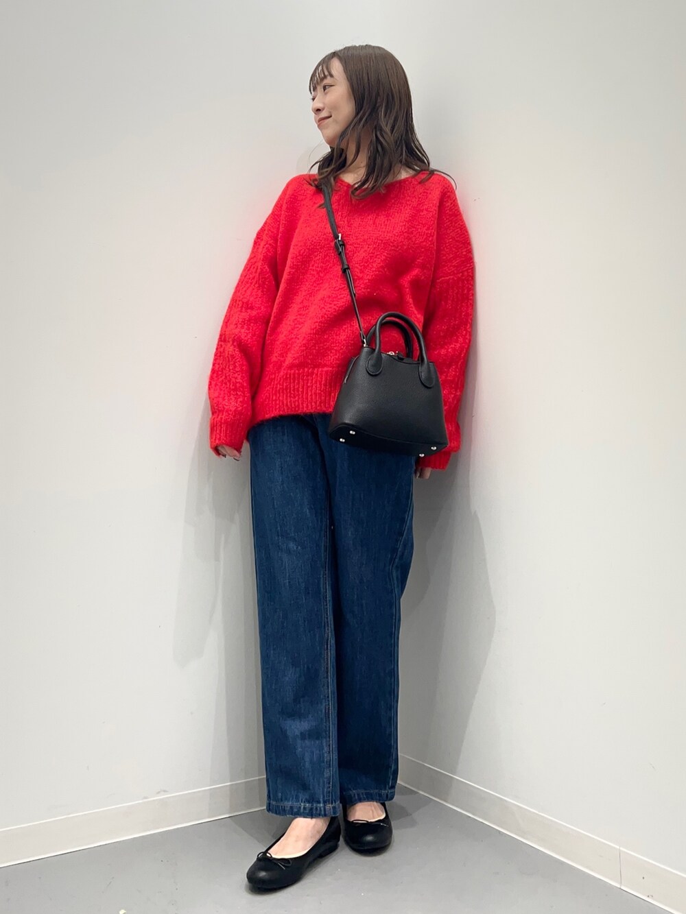 レッド系のニット/セーター、ブルー系のデニムパンツを着用したレディースの秋コーディネートの5枚目の写真