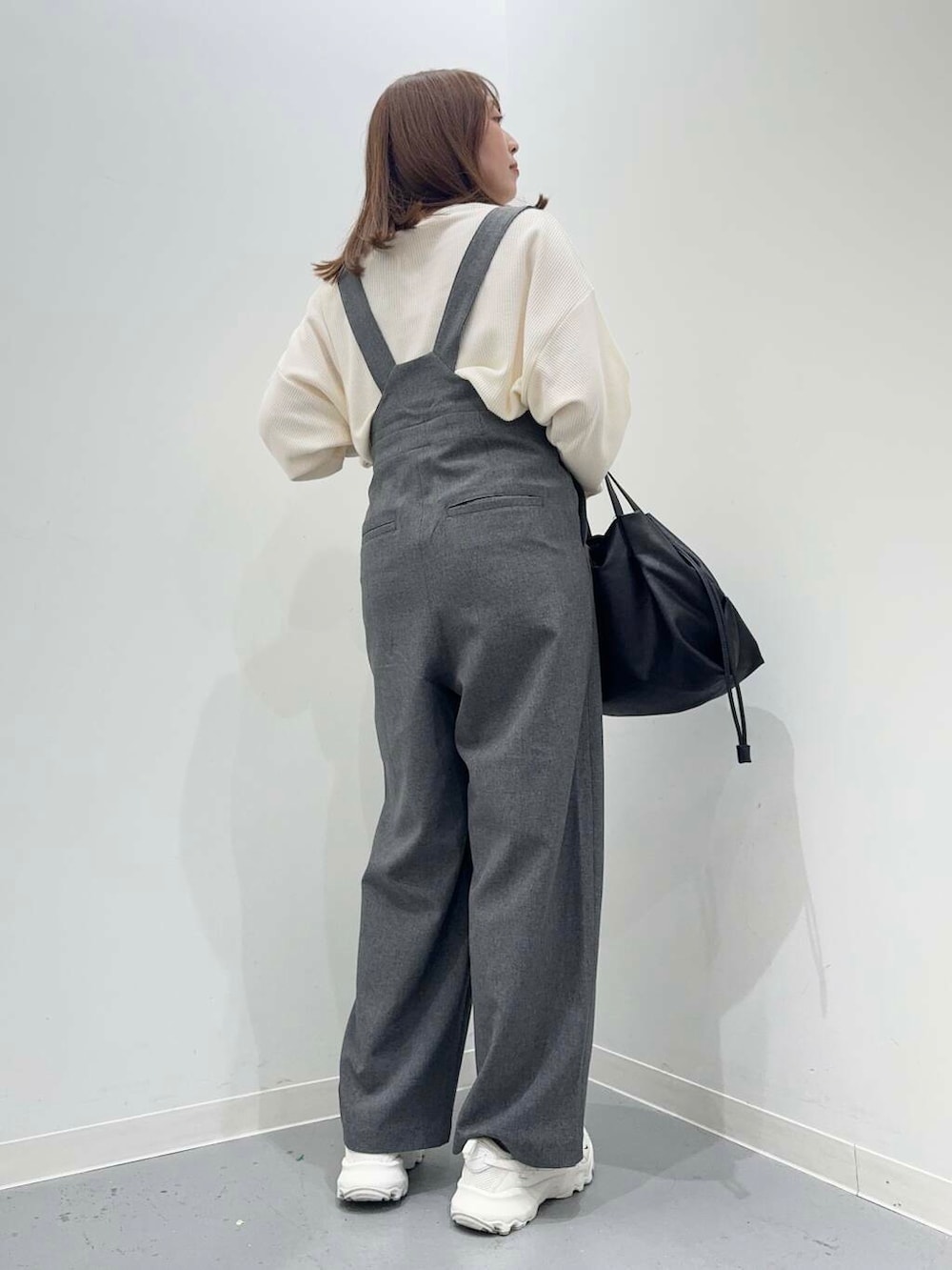 ホワイト系のショルダーバッグ、ホワイト系のスニーカー、グレー系のサロペット/オーバーオールを着用したレディースの秋コーディネートの2枚目の写真