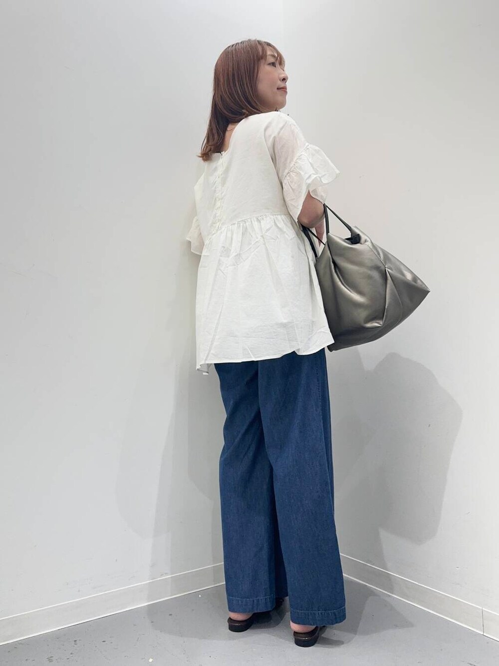 シルバー系のショルダーバッグ、ブルー系のデニムパンツ、ホワイト系のシャツ/ブラウスを着用したレディースの夏コーディネートの3枚目の写真