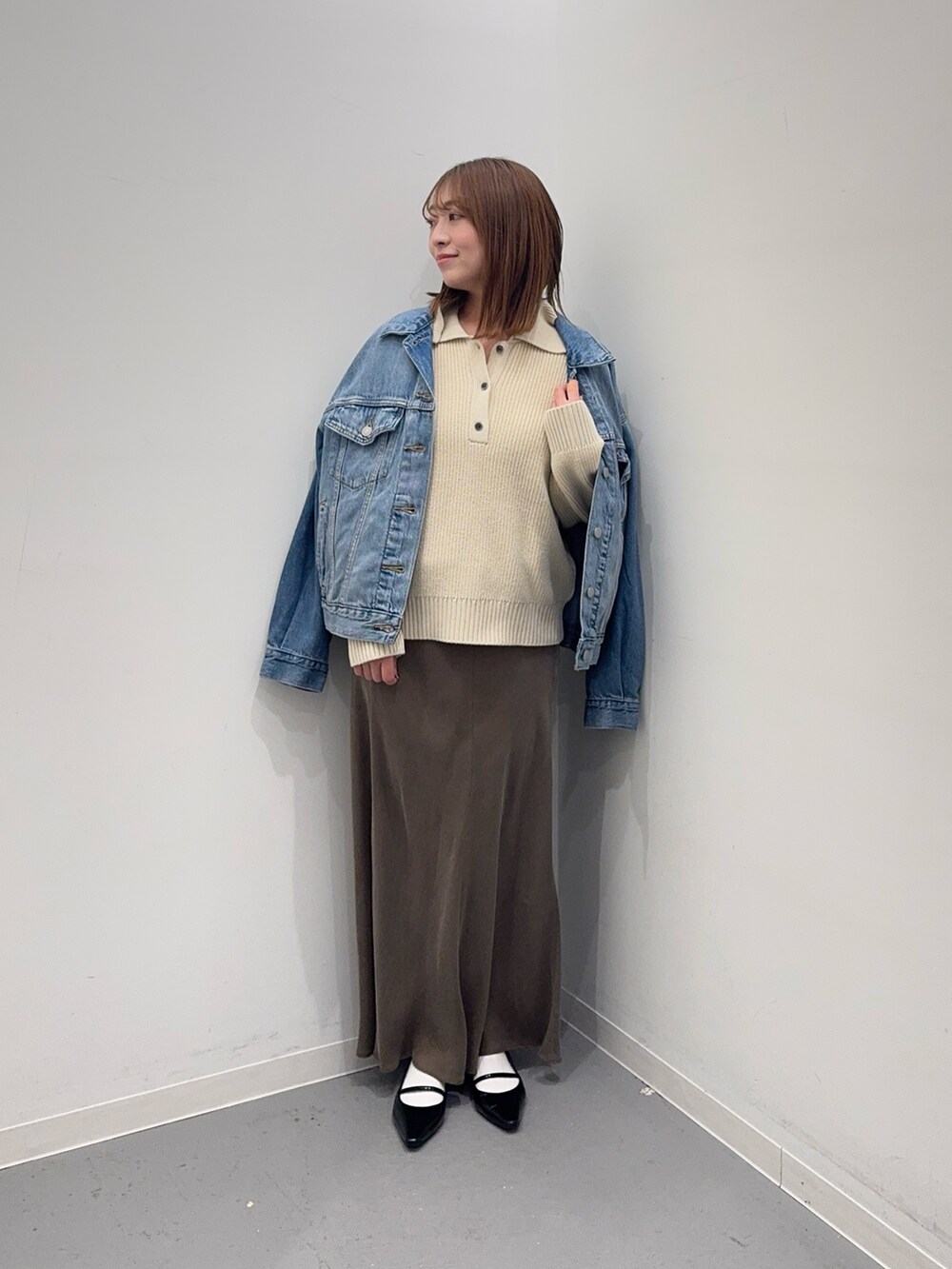 ホワイト系のニット/セーター、ブラウン系のスカート、ブルー系のデニムジャケットを着用したレディースの冬コーディネートの4枚目の写真