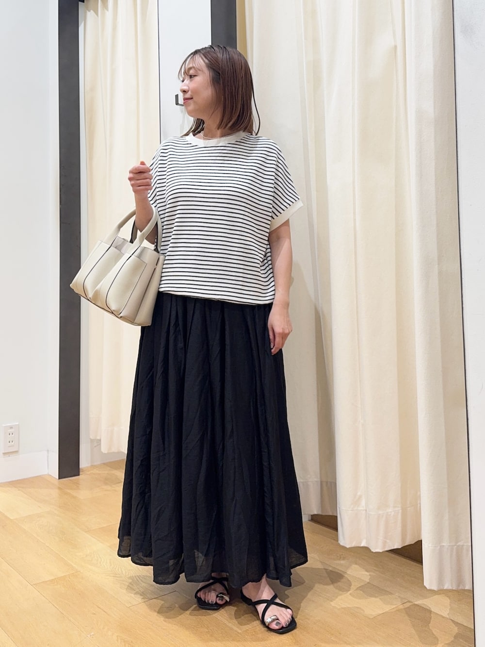 ホワイト系のTシャツ/カットソー、ブラック系のサンダル、ブラック系のスカートを着用したレディースの夏コーディネートの2枚目の写真