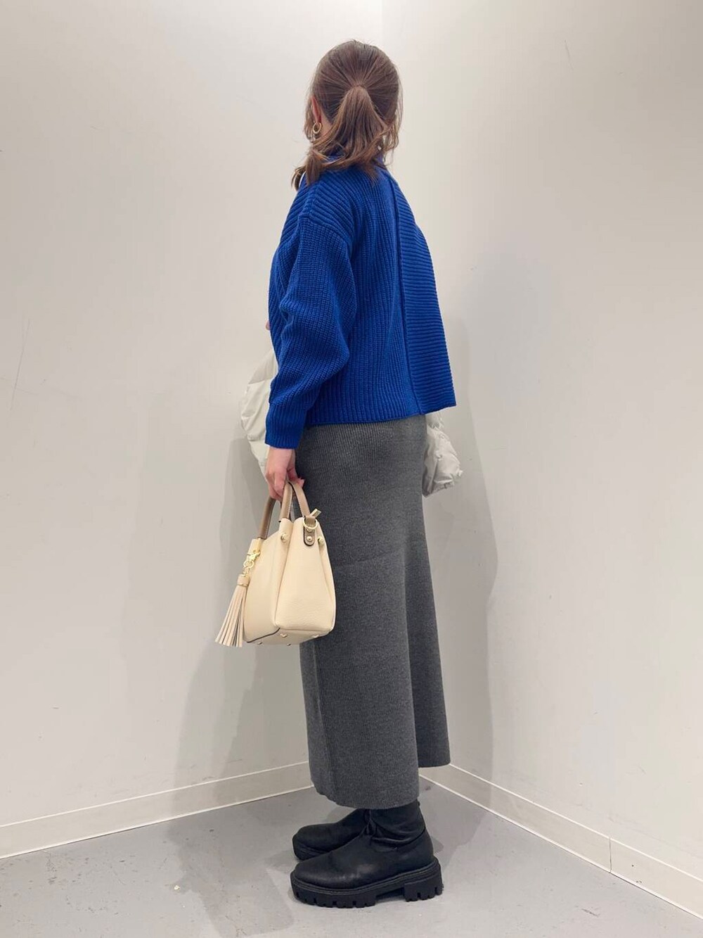 ホワイト系のトートバッグ、ブラック系のブーツ、グレー系のダウンジャケット/コートを着用したレディースの冬コーディネートの6枚目の写真