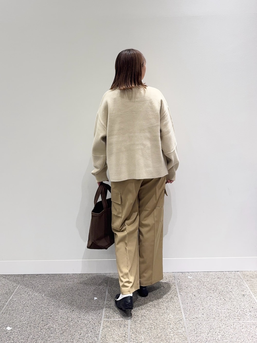 ベージュ系のニット/セーター、ホワイト系のTシャツ/カットソー、ブラウン系のトートバッグを着用したレディースの秋コーディネートの4枚目の写真