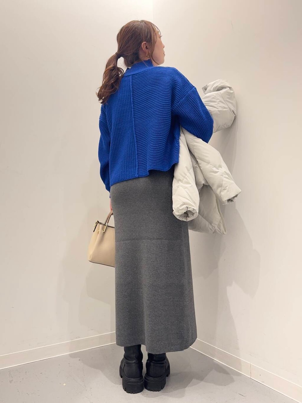 ホワイト系のトートバッグ、ブラック系のブーツ、グレー系のダウンジャケット/コートを着用したレディースの冬コーディネートの7枚目の写真