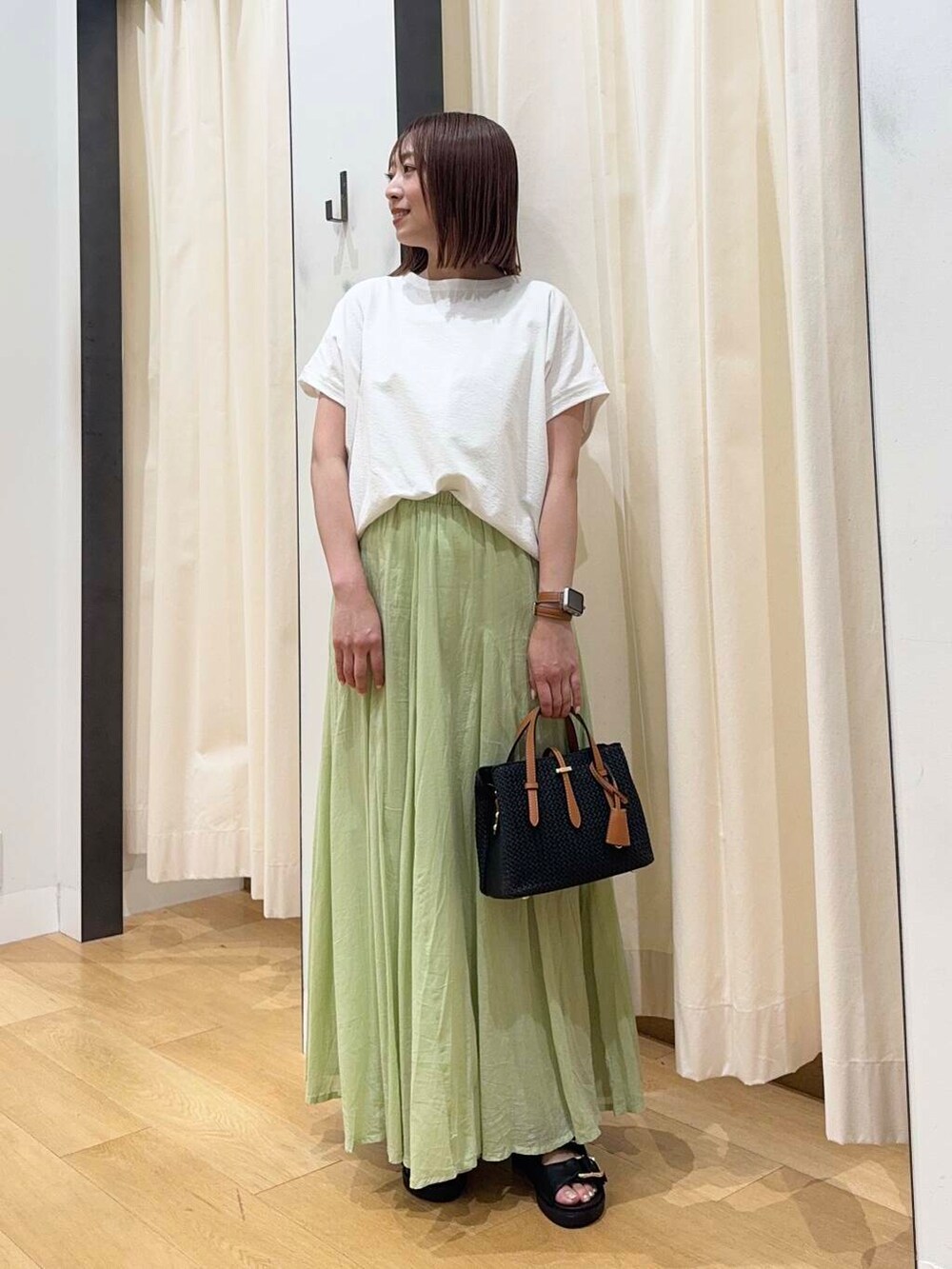 ブラック系のトートバッグ、ブラック系のサンダル、グリーン系のスカートを着用したレディースの夏コーディネートの2枚目の写真