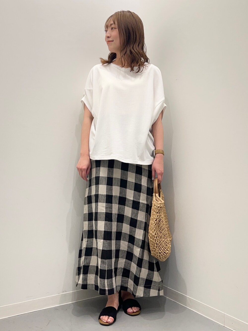 ホワイト系のTシャツ/カットソー、ブラック系のスカート、ベージュ系のかごバッグを着用したレディースの春コーディネートの3枚目の写真