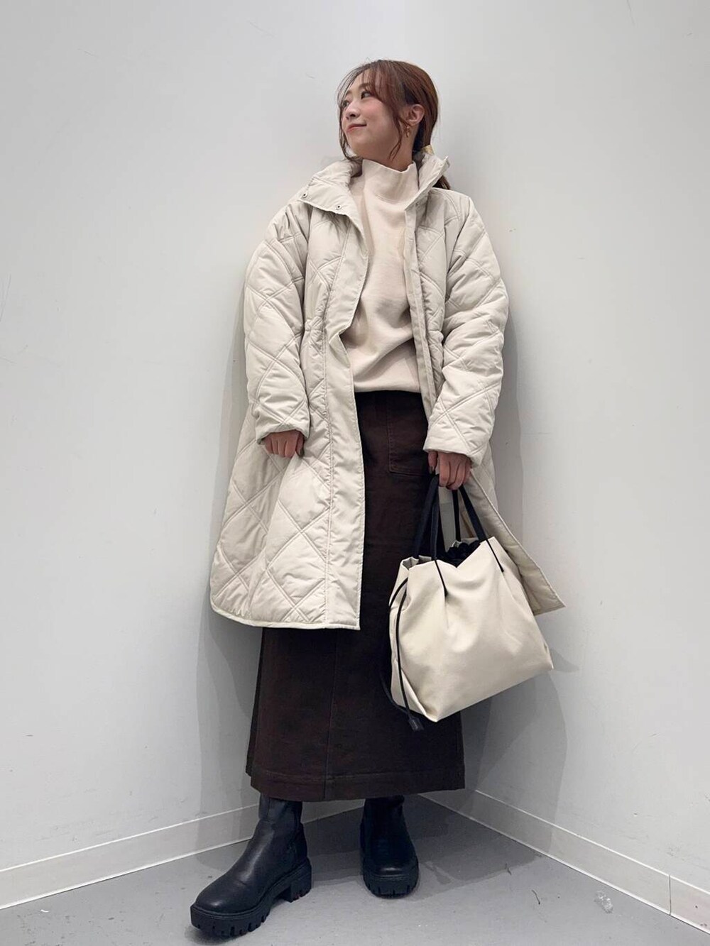 ホワイト系のショルダーバッグ、ブラック系のブーツ、ベージュ系のその他アウターを着用したレディースの冬コーディネートの9枚目の写真