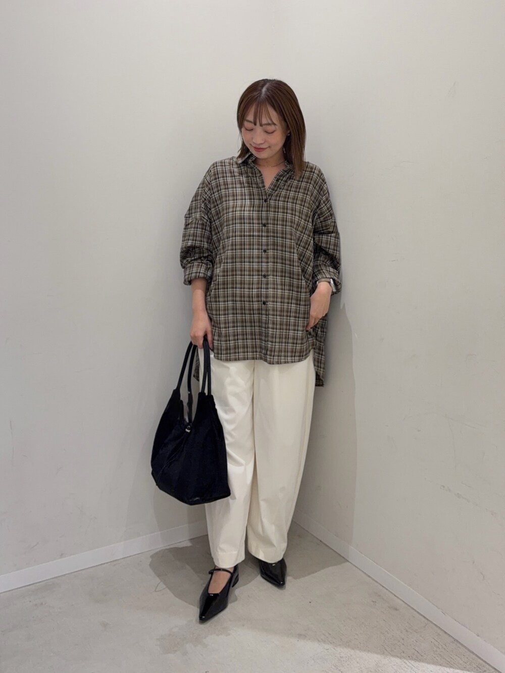 ブラウン系のシャツ/ブラウス、ホワイト系のその他パンツ、ブラック系のトートバッグを着用したレディースの秋コーディネートの5枚目の写真