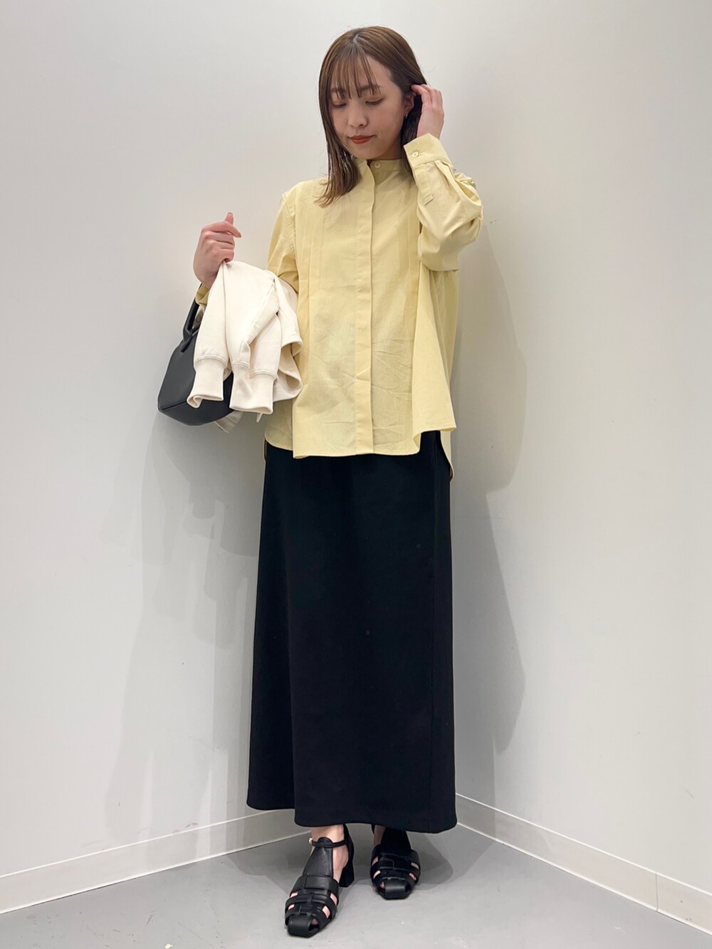 イエロー系のシャツ/ブラウス、ブラック系のスカート、ホワイト系のカーディガン/ボレロを着用したレディースの春コーディネートの6枚目の写真