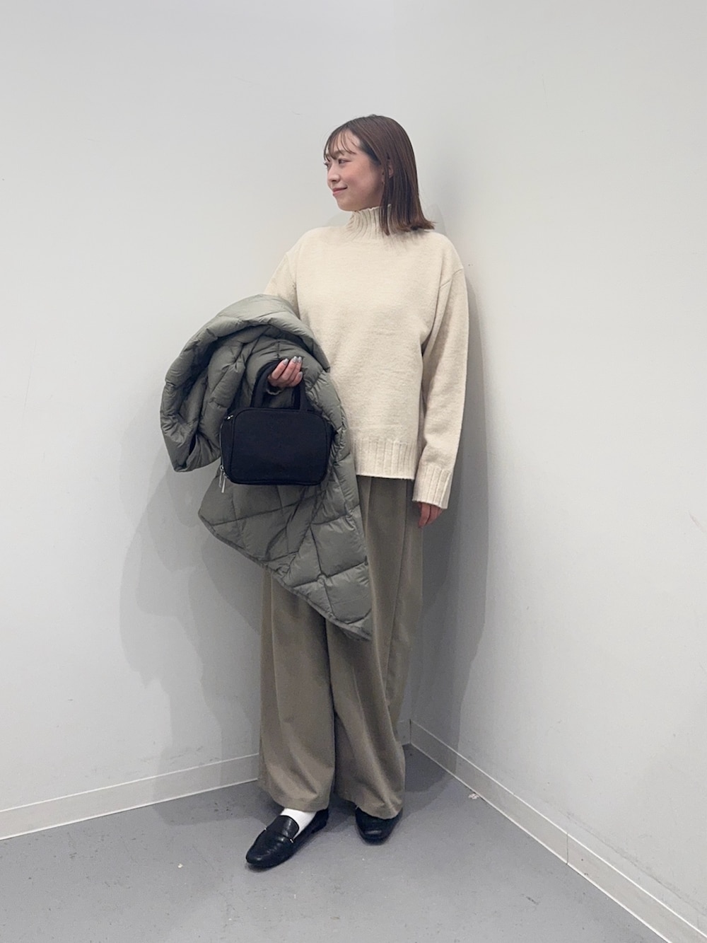 グリーン系のダウンジャケット/コート、ホワイト系のニット/セーター、ブラック系のボストンバッグを着用したレディースの冬コーディネートの4枚目の写真
