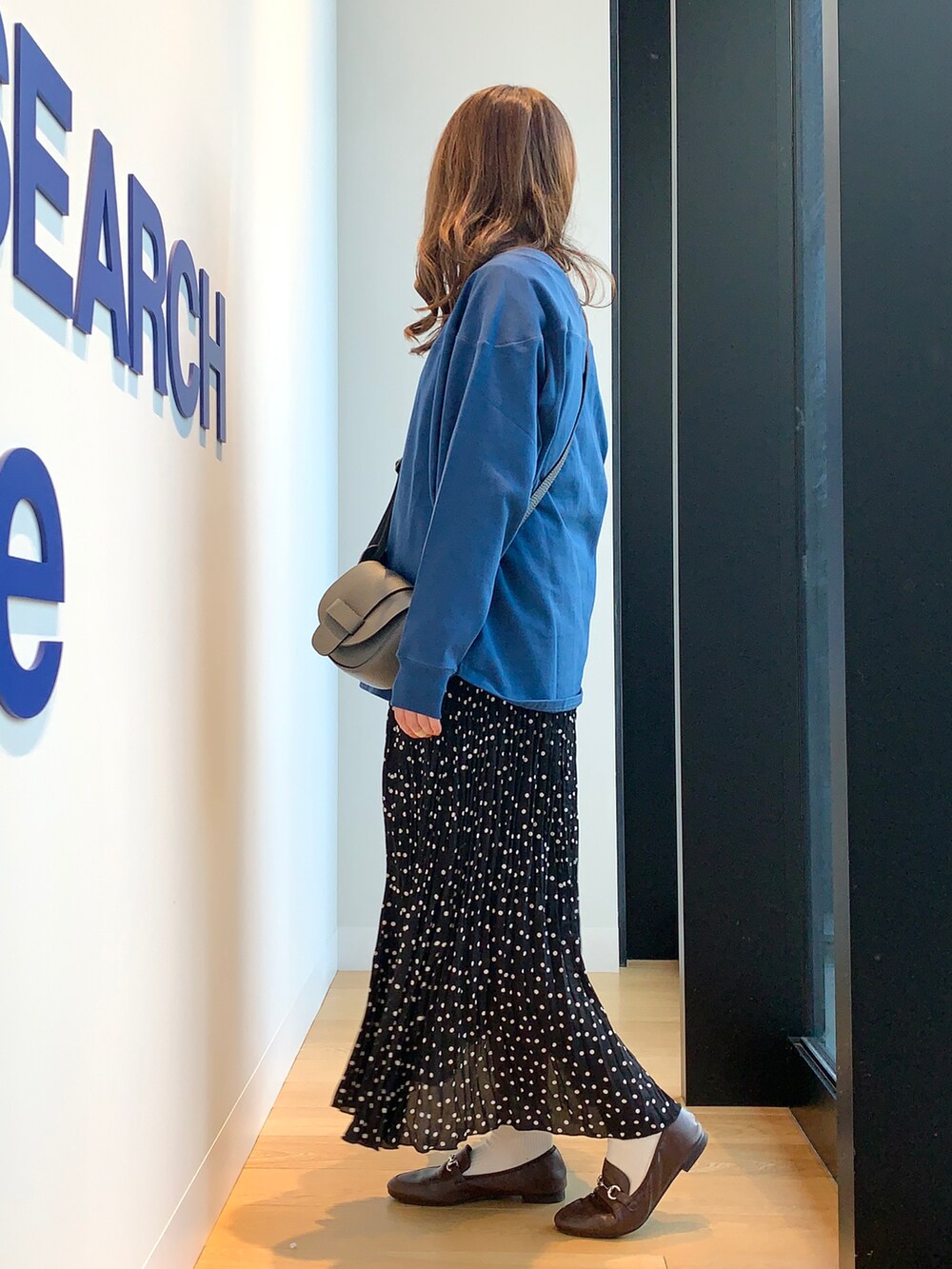 ブルー系のスウェット、ブラック系のスカート、ブラウン系のローファーを着用したレディースの冬コーディネートの2枚目の写真