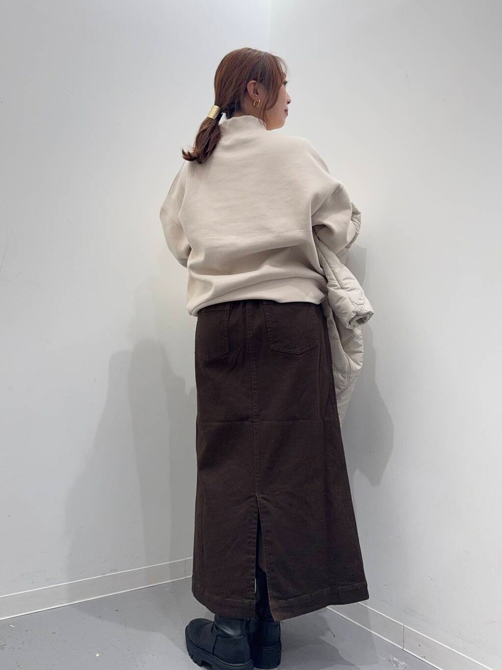 ホワイト系のショルダーバッグ、ブラック系のブーツ、ベージュ系のその他アウターを着用したレディースの冬コーディネートの4枚目の写真