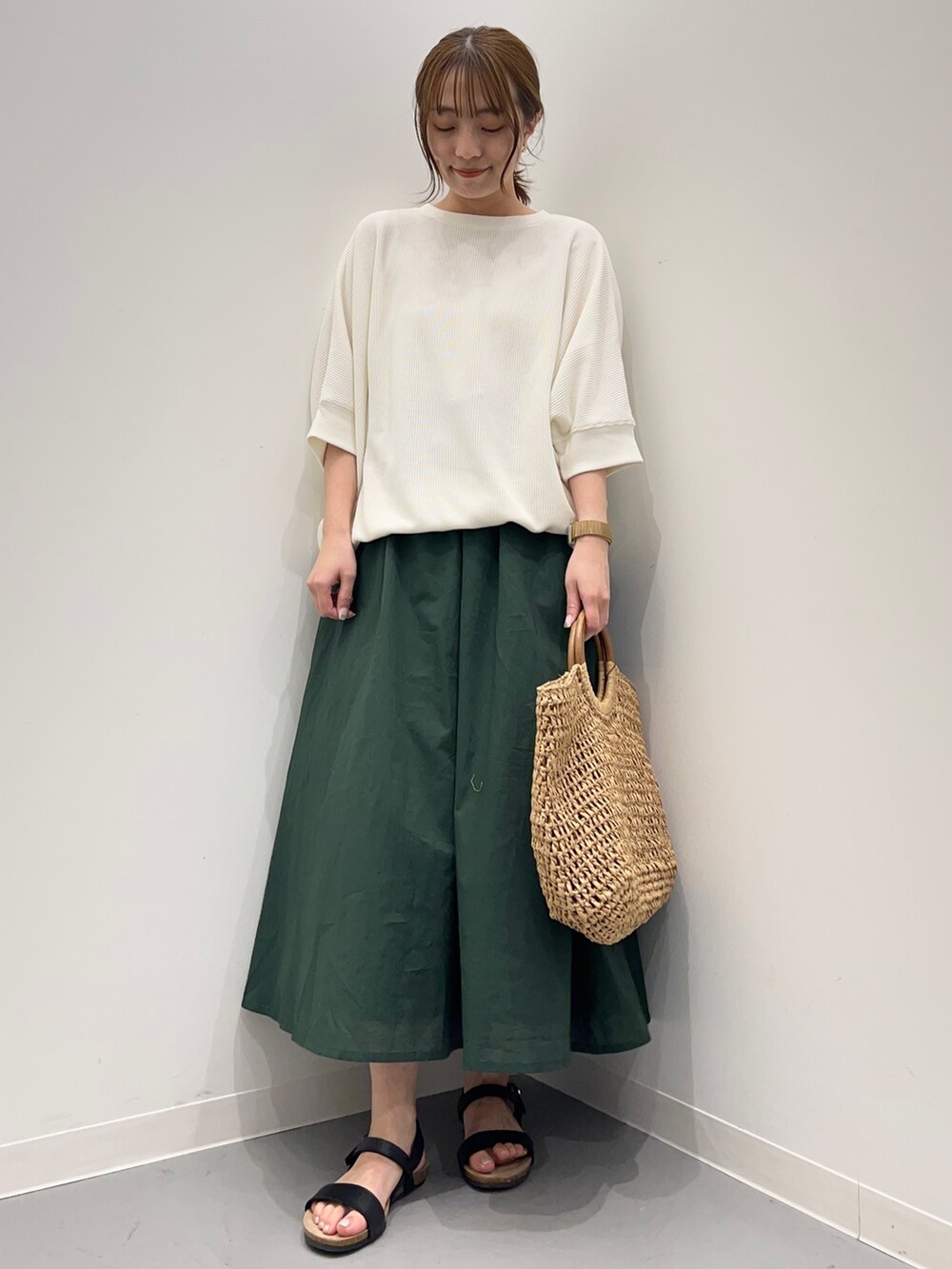 ベージュ系のTシャツ/カットソー、グリーン系のスカート、ブラック系のサンダルを着用したレディースの春コーディネートの2枚目の写真