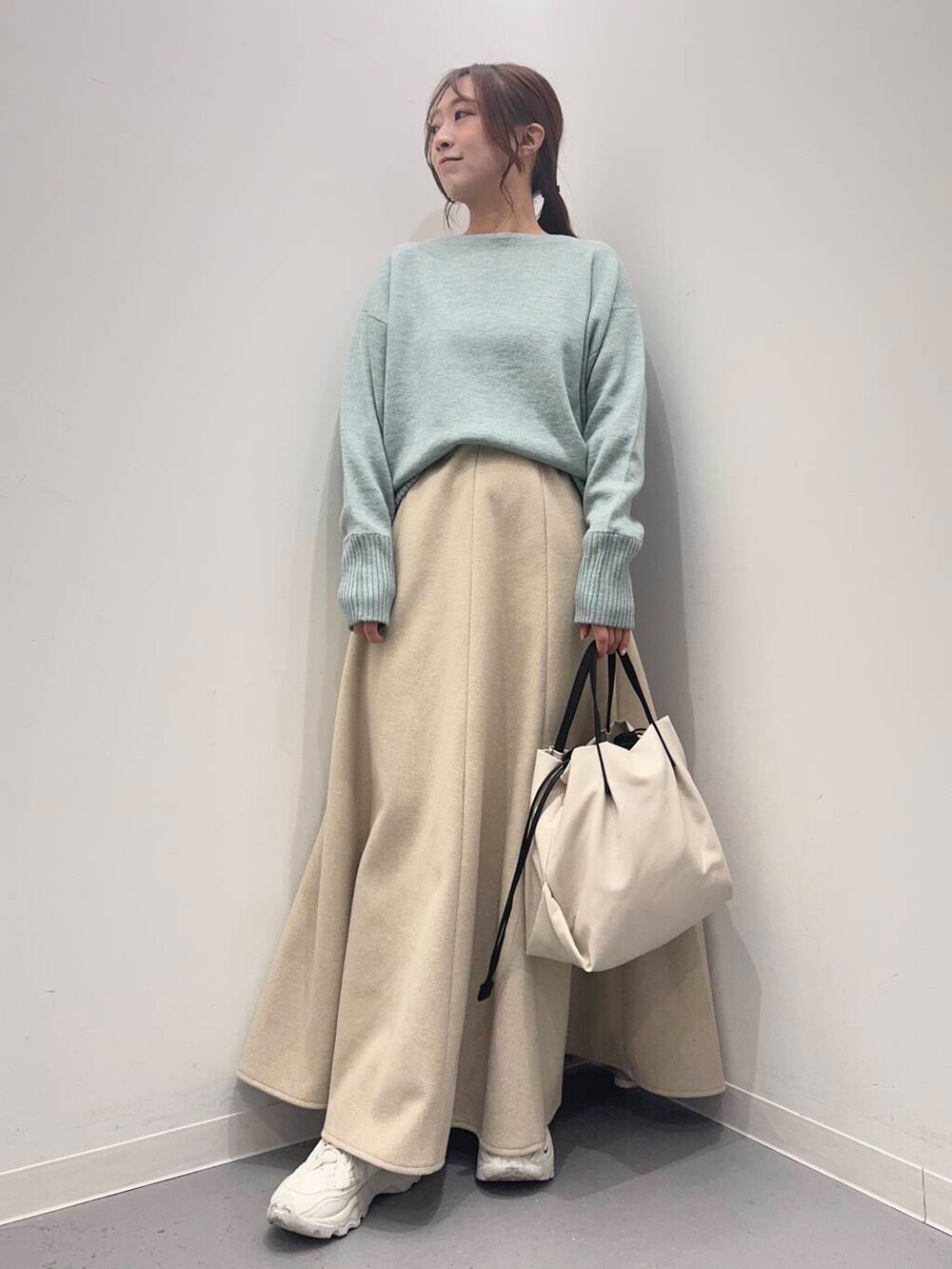 ホワイト系のショルダーバッグ、ホワイト系のスニーカー、グリーン系のニット/セーターを着用したレディースの冬コーディネートの5枚目の写真