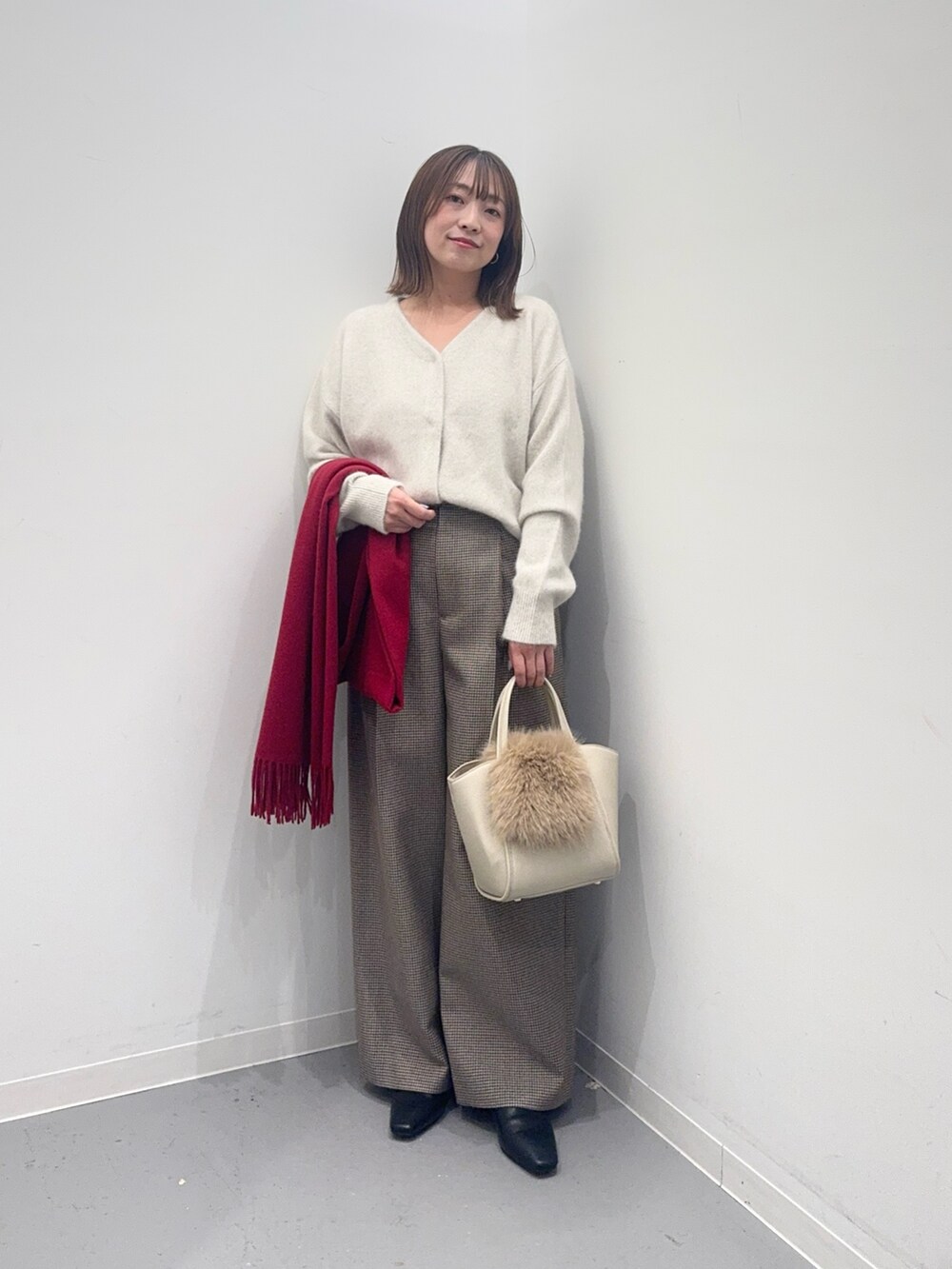 ベージュ系のハンドバッグ、ホワイト系のカーディガン/ボレロ、グリーン系のその他パンツを着用したレディースの冬コーディネートの4枚目の写真