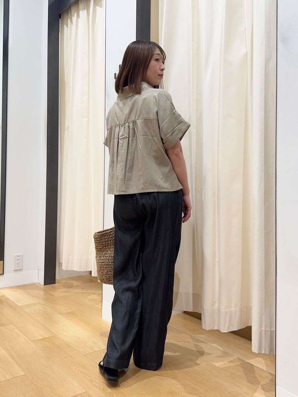 ベージュ系のトートバッグ、ブラック系のデニムパンツ、ブラック系のサンダルを着用したレディースの夏コーディネートの3枚目の写真