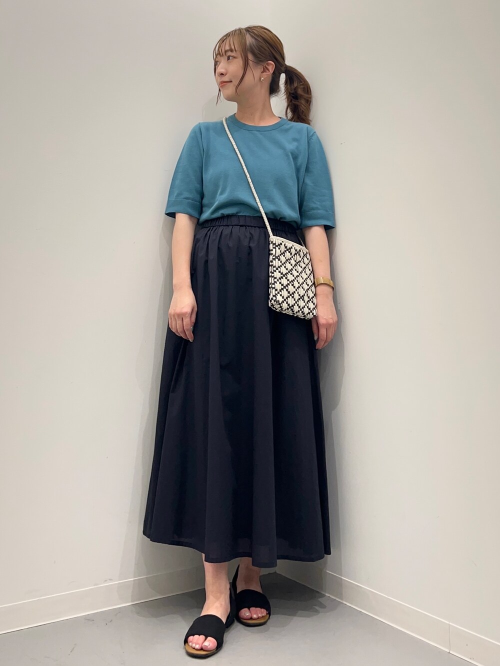 ブルー系のニット/セーター、ブルー系のスカート、ブラック系のサンダルを着用したレディースの春コーディネートの5枚目の写真