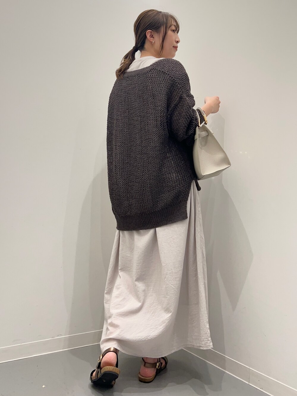 グレー系のワンピース、グレー系のカーディガン/ボレロ、ホワイト系のハンドバッグを着用したレディースの夏コーディネートの4枚目の写真