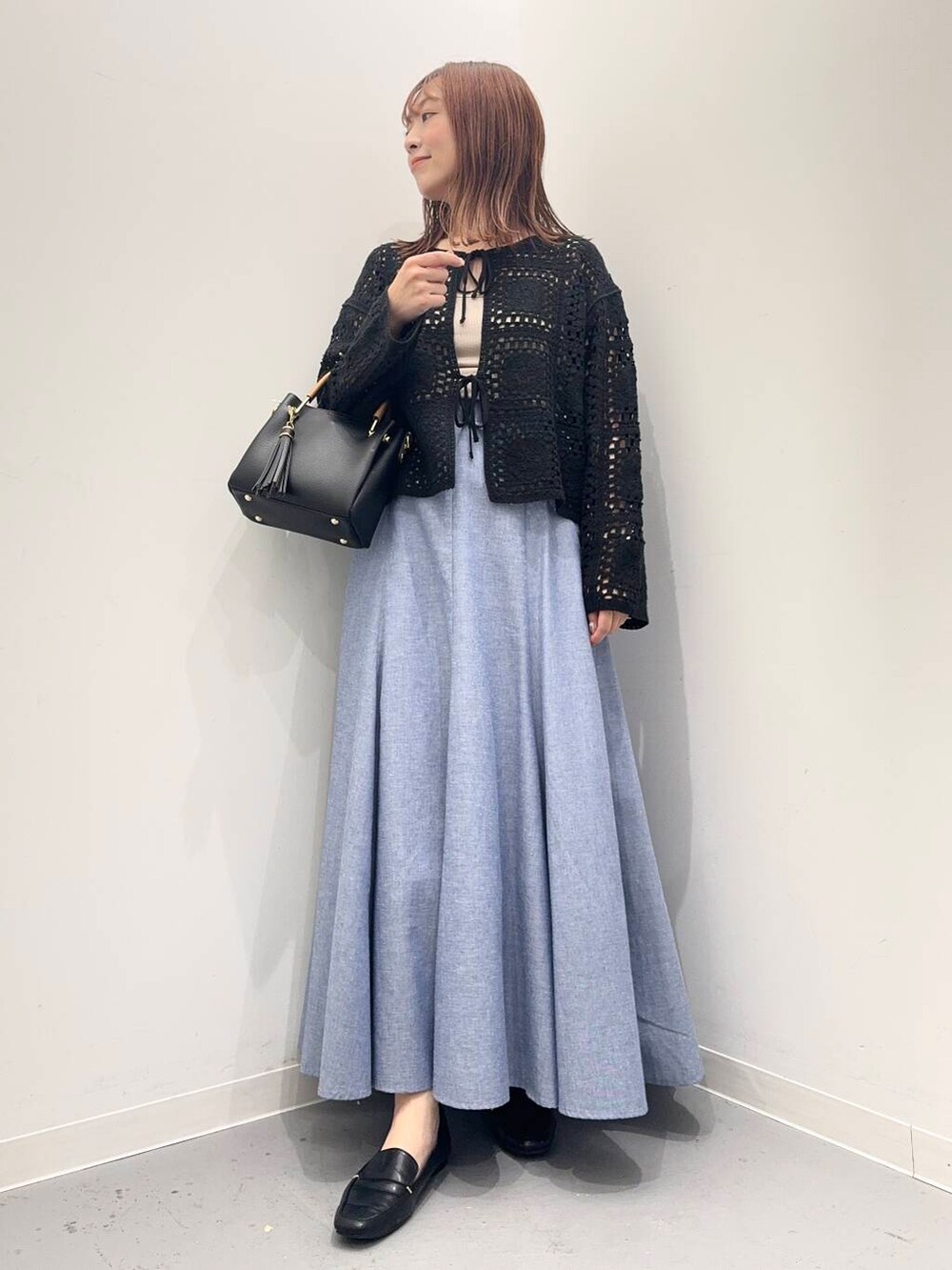 ブラック系のローファー、ブラック系のトートバッグ、ブルー系のスカートを着用したレディースの夏コーディネートの2枚目の写真